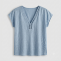 A light blue short-sleeve linen top with a V-neckline featuring a decorative cutout lace detail, shown against a light gray background.